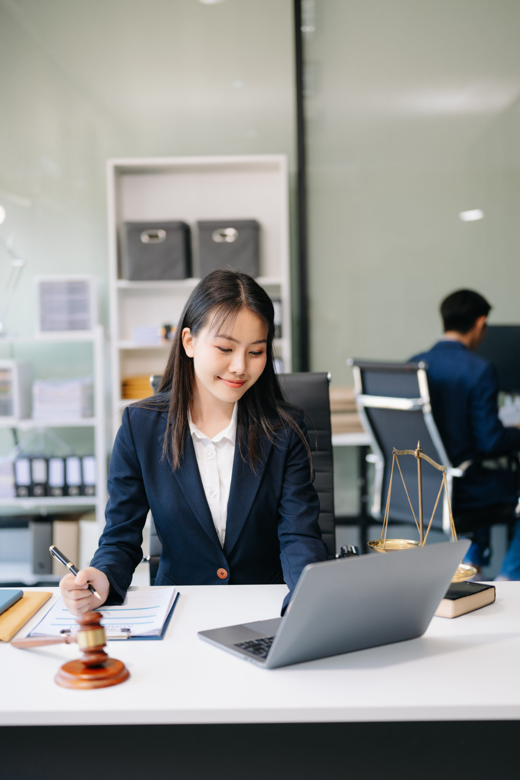 Asian woman lawyer working and gavel, tablet, laptop in front, A Smiling Asian woman lawyer working on laptop and documents with a gavel nearby, symbolizing efficient legal process outsourcing services.
