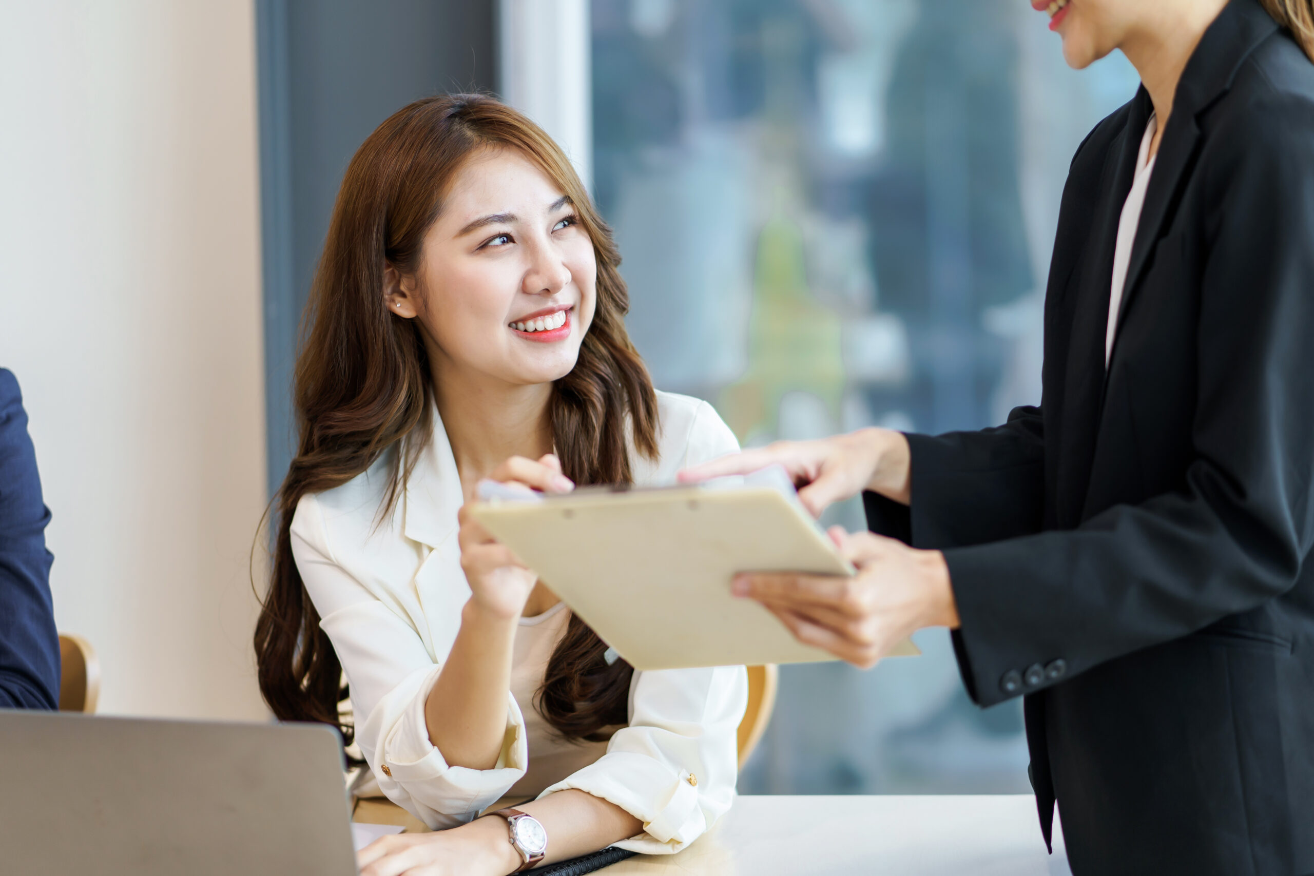 Meeting of successful Asian business people sitting and smile ha Smiling Asian businesswoman receiving documents, symbolizing efficient handover and collaborative processes in remote staffing environments.