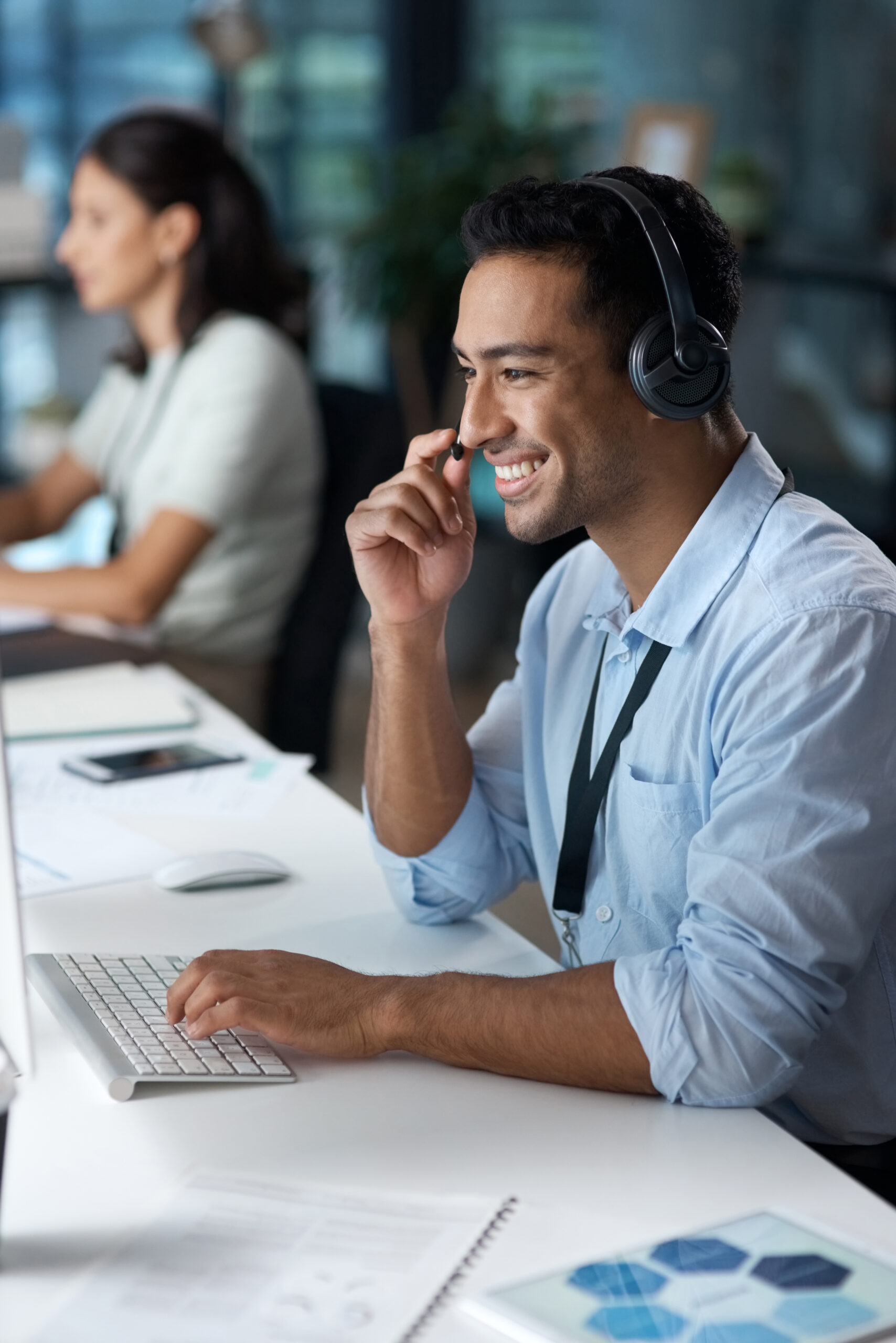 Dedicated-BPO-Agent-Providing-Customer-Support-in-the-Philippines Smiling male BPO agent with headset actively working at a computer, demonstrating professional and friendly customer support.