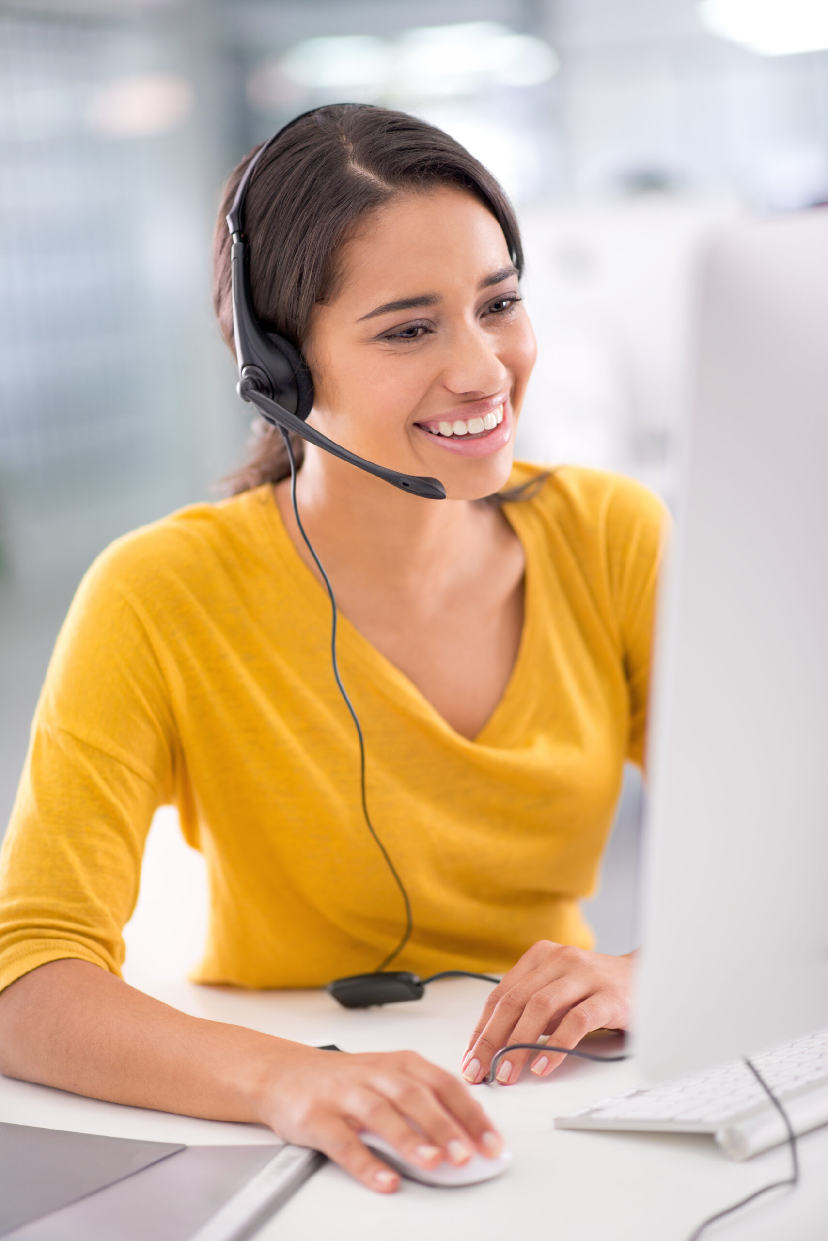 She tries her best to meet the customers' needs A smiling young customer service representative with a headset working at a computer, providing friendly support for Business process outsourcing solutions.