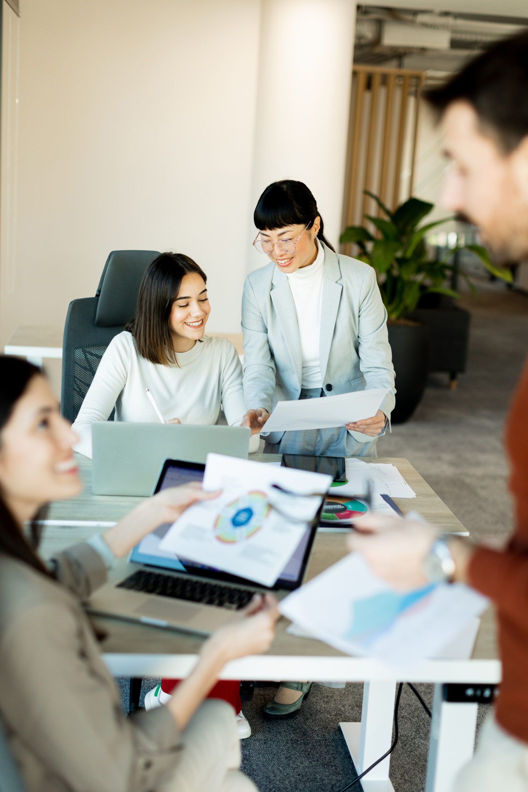 Team collaboration thrives in a modern office setting during a p Diverse team members collaborating and exchanging documents in a bright, modern office, showcasing efficient workflow for remote staffing.